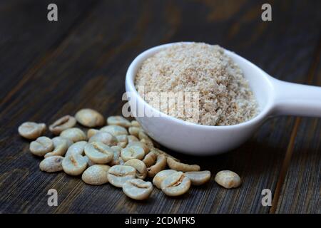 Green coffee beans and unroasted coffee powder in spoon, Germany Stock Photo