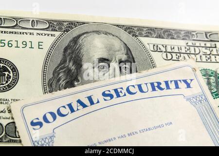 Macro view of Benjamin Franklin on the one hundred dollar bill looking over the top of a old Social Security Card Stock Photo