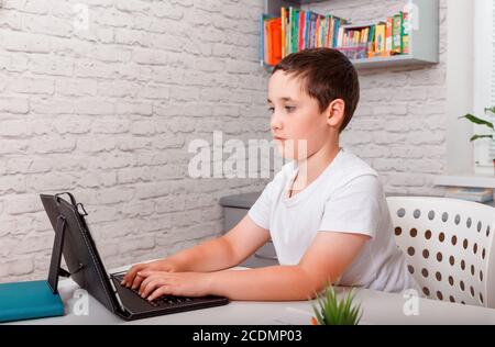Preteen schoolboyl using gadgets to study at home. Homeschooling Stock Photo