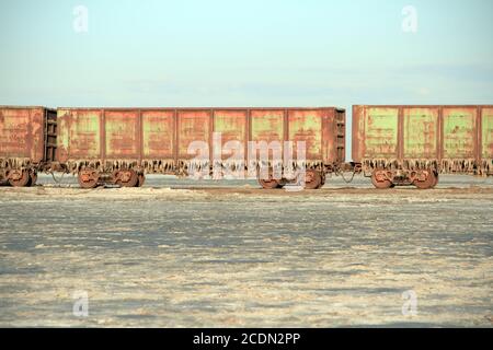 Old rusty train cars with stalactites of salt in the lake Baskunchak Stock Photo