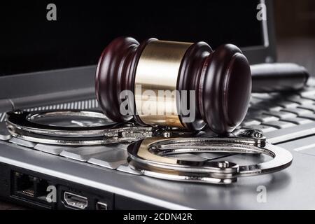 handcuffs and judge gavel on computer concept Stock Photo