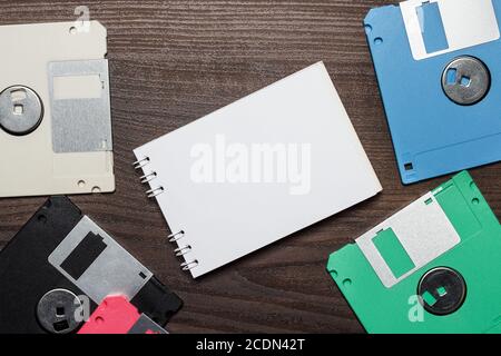 diskettes and blank notebook on wooden background Stock Photo