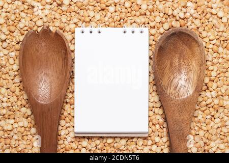 notebook and wooden spoons over peas background Stock Photo