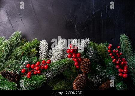 Christmas frame concept with xmas tree branches and red holiday decor on grey stone background with copy space