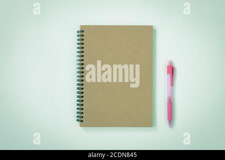 Brown Cover Spiral Notebook or Spring Notebook in Unlined Type and Pink Pen on Blue Pastel Minimalist Background. Spiral Notebook Mockup on Center Fra Stock Photo