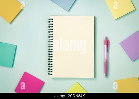 Spiral Notebook or Spring Notebook in Unlined Type and Multi Color Sticky Note and Pink Pen on Blue Pastel Minimalist Background. Spiral Notebook Mock Stock Photo