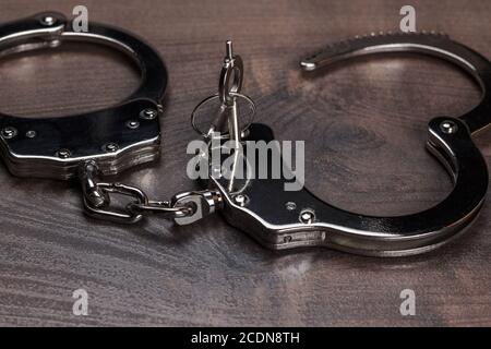 handcuffs and keys on brown wooden table background Stock Photo