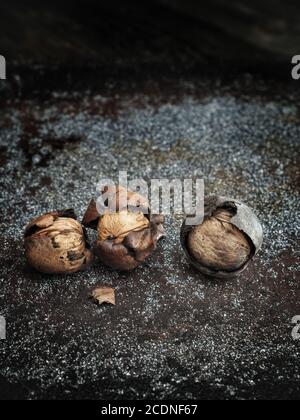 Three harvested walnuts on dark vintage background. Stock Photo