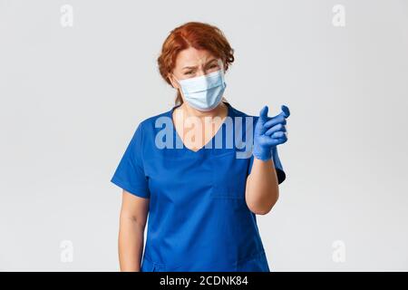 Medical workers, covid-19 pandemic, coronavirus concept. Disappointed and complaining female doctor, nurse or physician showing something too tiny and Stock Photo