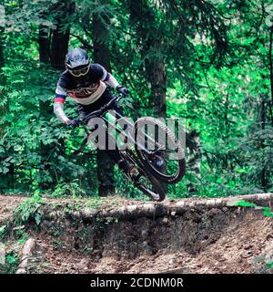 Russia, Moscow - August 29, 2020: Young boy jumping with his MTB Bike at forest. Professional downhill riding. Biker riding in nature. Cool athlete cy Stock Photo