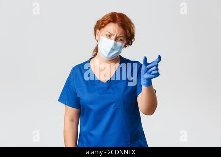 Medical workers, covid-19 pandemic, coronavirus concept. Disappointed and complaining female doctor, nurse or physician showing something too tiny and Stock Photo