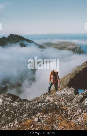 Man traveler hiking above clouds in mountains travel active lifestyle climbing solo to summit summer vacation outdoor adventure journey in Norway Stock Photo