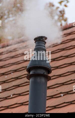 Old smoking chimney on a tile roof Stock Photo