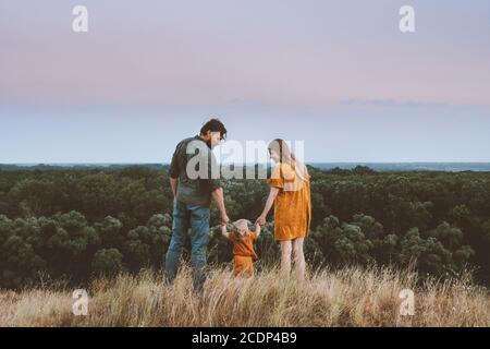 Family parents mother and father with baby holding hands walking outdoor together healthy lifestyle rural nature forest landscape Stock Photo