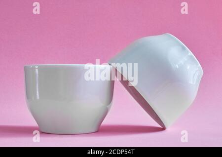 Two white ceramic cups without handles on a pink background Stock Photo