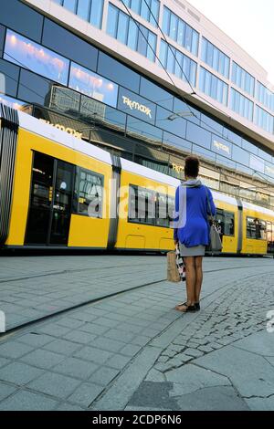 young woman waiting on the roadside at Alexanderplatz in Berlin and lets a tram passing Stock Photo