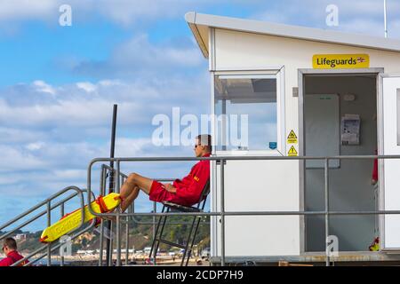 Bournemouth, Dorset UK. 29th August 2020. UK weather: cool and breezy with the odd glimmer of sunshine. Few people at Bournemouth beaches as yet for the start of the long Bank Holiday weekend - not the usual Bank Holiday crowds heading to the seaside!  RNLI Lifeguards on patrol at Lifeguards kiosk hut. Credit: Carolyn Jenkins/Alamy Live News Stock Photo