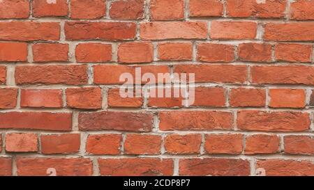 A smooth solid wall of old red historical bricks worn by time. Background from the wall. Stock Photo