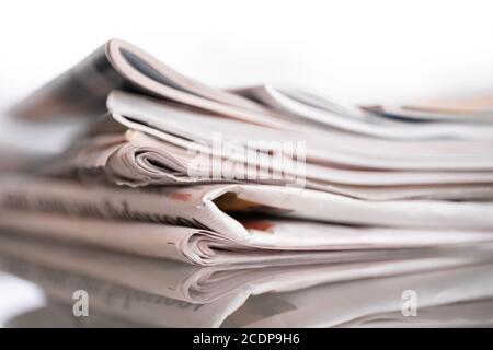 Stack of newspapers and magazines with narrow depth of field on white. Background image Stock Photo