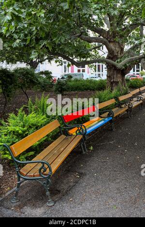 Bunte Parkbank inmitten normaler Bänke 2 Stock Photo