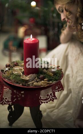 Victorian seeming Christmas scene with young redheaded woman in a antique dress with candle Stock Photo