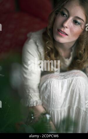 Victorian, historic seeming Christmas scene with young redheaded woman in a antique dress Stock Photo