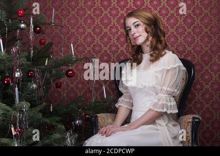 Victorian, historic seeming Christmas scene with young redheaded woman in a antique dress Stock Photo