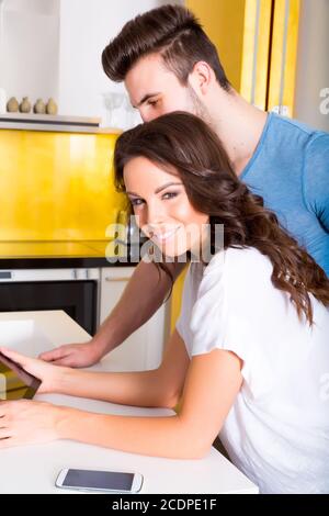 Young couple using a Tablet PC in the kitchen at home Stock Photo
