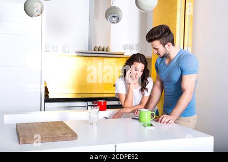 Young couple using a Tablet PC in the kitchen at home Stock Photo