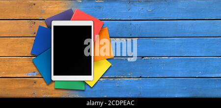 tablet, books in rainbow colors on the table from the old boards, front view Stock Photo