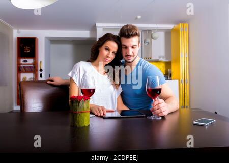 Young couple using a Tablet PC while having a glass of wine Stock Photo