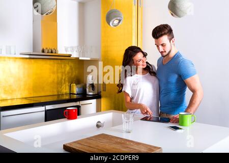 Young couple using a Tablet PC in the kitchen at home Stock Photo