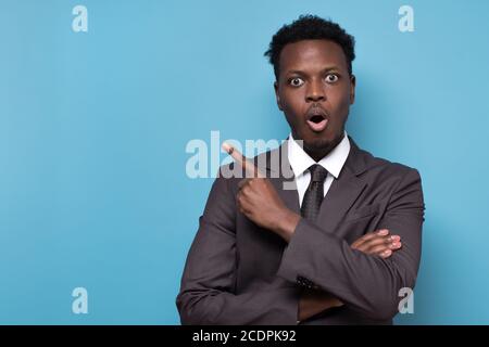 Funny young african american man in suit pointing index fingers aside up. Stock Photo