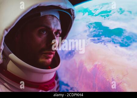 Astronaut looking planet earth from the window of his capsule. Concept about science and space exploration Stock Photo