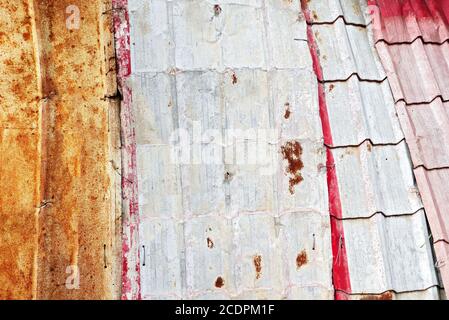 Detail view of old rusty and painted metal sheets used as roofing, held together with metal wire only, often seen in Asia Stock Photo