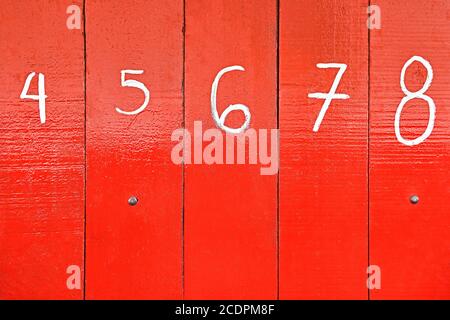 The entrance of a shop is closed with red painted wooden panels, which are marked with big white numbers. It is often seen in the Philippines, Asia. Stock Photo