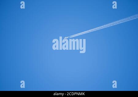 Airplane leaves chemical traces in the blue sky Stock Photo