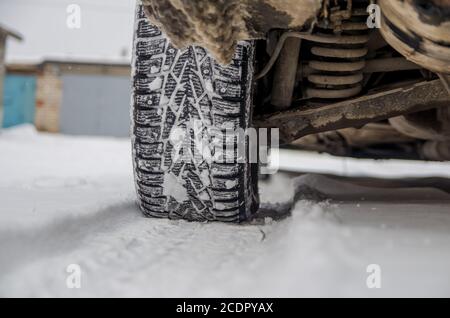 The car tire in the snow close up. Car tracks on the snow. Traces of the car in the snow. Winter tires. Tyres covered with snow at winter road Stock Photo