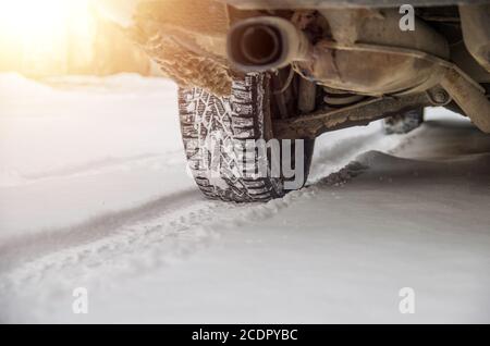 The car tire in the snow close up. Car tracks on the snow. Traces of the car in the snow. Winter tires. Tyres covered with snow at winter road Stock Photo