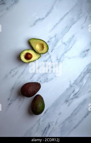 set of cut or uncut avocados on a white marble base Stock Photo