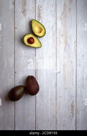 set of avocados, cut and uncut, on a clear background of deteriorated and white wood Stock Photo