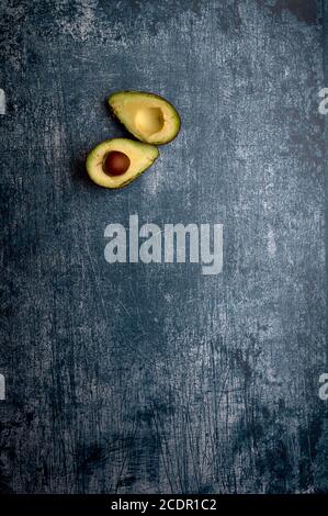 set of avocados, cut and uncut, on a dark blue, metallic, cement, marble, stone background Stock Photo