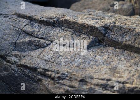 surface of a rock up close with layers and cracks indicating where the rock will eventually disintegrate into smaller pieces Stock Photo