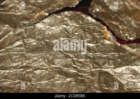 Crumpled and torn golden bronze shiny foil texture background Stock Photo