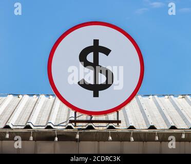 A Circle billboard with icon a symbol of dollar, is installed on a roof. Board with sign of currency. Stock Photo