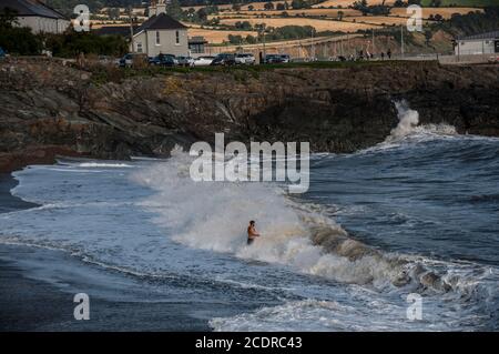Visiting Greystones.  Mid age man stays in front of breaking wave enjoying its splashing. Stock Photo