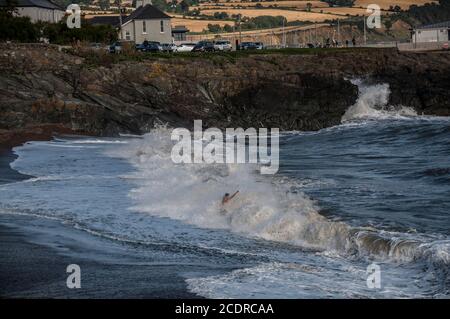 Visiting Greystones.  Mid age man stays in front of breaking wave enjoying its splashing. Stock Photo