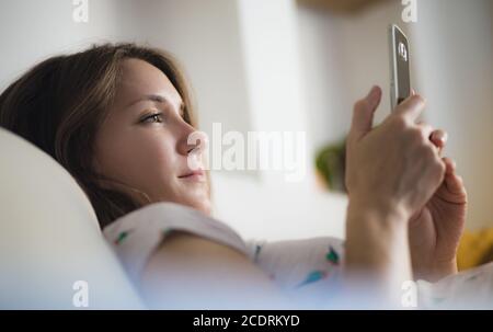 Young woman using mobile phone at home smiling Stock Photo