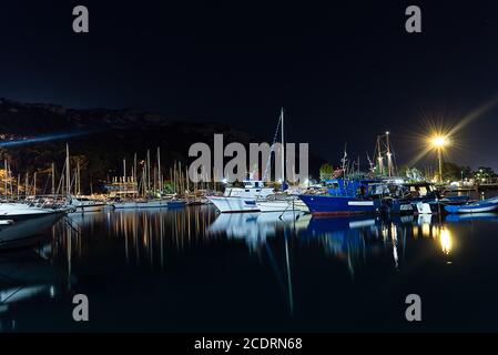 Cagliari, Sardinia, Italy - August 28 2020: lots of fisherman's boats moored at city pier at night with water reflections Stock Photo