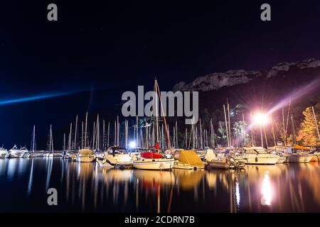 Cagliari, Sardinia, Italy - August 28 2020: lots of boats moored at city pier at night, with water reflections and lights - Sella del diavolo on backg Stock Photo